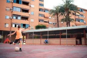 ragazzino gioca a calcio nel cortile di condominio