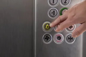 mano che preme pulsante di emergenza di un ascensore bloccato