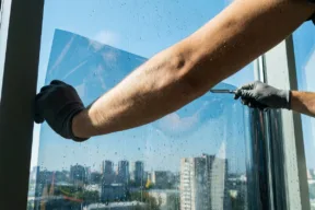 una persona applica la pellicola sul vetro