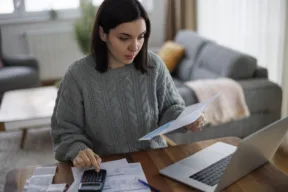 una persona legge le bollette e fa i calcoli