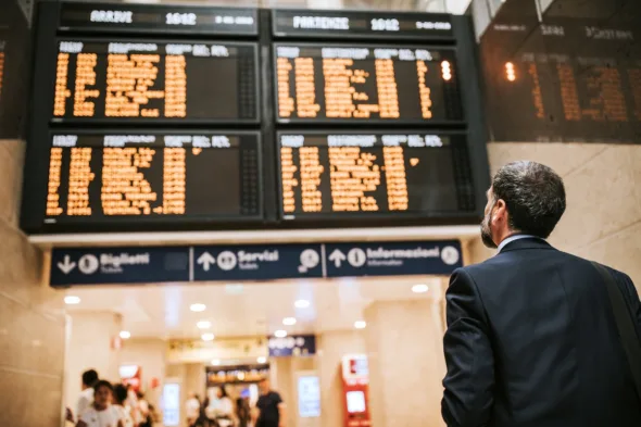 uomo guarda tabellone orari treni