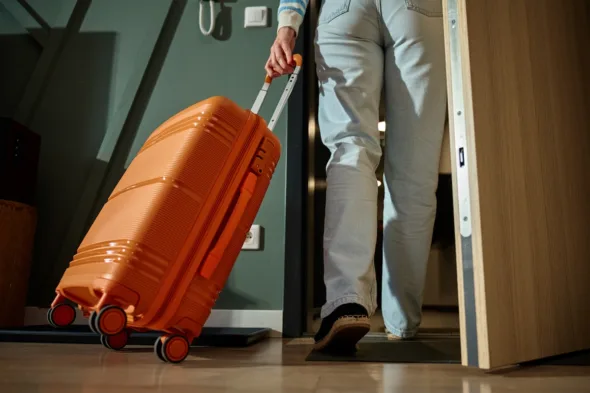 persona esce di casa con la valigia