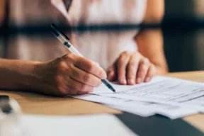 una persona firma un documento